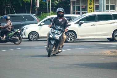 Cakarta, Endonezya Kasım 2022. Jakarta 'nın varoşlarındaki işlek bir caddede araba süren bir motosikletlinin ön görüntüsü.