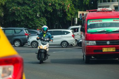 Cakarta, Endonezya Kasım 2022. Jakarta 'nın varoşlarındaki işlek bir caddede araba süren bir motosikletlinin ön görüntüsü.