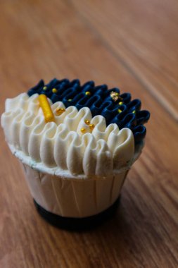 Lüks ve zarif kekler, beyaz kremalı ve lacivert üzerine altın serpiştirilmiş. Tatlı ve kremalı bir tadı var..