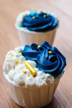 Lüks ve zarif kekler, beyaz kremalı ve lacivert üzerine altın serpiştirilmiş. Tatlı ve kremalı bir tadı var..