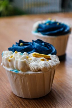 Lüks ve zarif kekler, beyaz kremalı ve lacivert üzerine altın serpiştirilmiş. Tatlı ve kremalı bir tadı var..