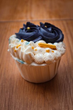 Lüks ve zarif kekler, beyaz kremalı ve lacivert üzerine altın serpiştirilmiş. Tatlı ve kremalı bir tadı var..