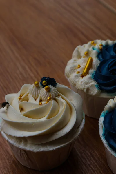 Luxurious and elegant cupcakes, with white cream and navy blue with gold sprinkles. It has a sweet and creamy taste.