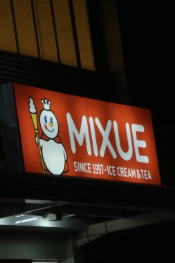 Bekasi, Indonesia on July 2022. Glowing MIXUE restaurant sign against night sky. Mixue is a popular cold beverage ice cream shop. It is originally from China and recently opens in Indonesia.