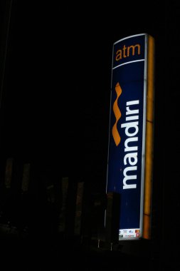 Bekasi, Indonesia in July 2022. The logo of Bank Mandiri shining brightly at night against the dark night sky. Bank Mandiri is one of the largest banks in Indonesia in terms of total assets, loans and deposits.