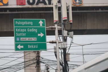 Bekasi, Indonesia on July 2022. Signs for directions to Pulo Gebang, Kelapa Gading, Sunter and Bekasi. This signpost is green with white writing and lines.
