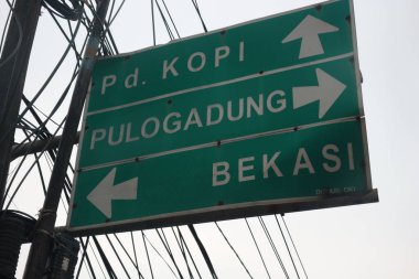 Bekasi, Indonesia on July 2022. Signs for directions to Pondok Kopi, Pulo Gadung and Bekasi. This signpost is green with white writing and lines.