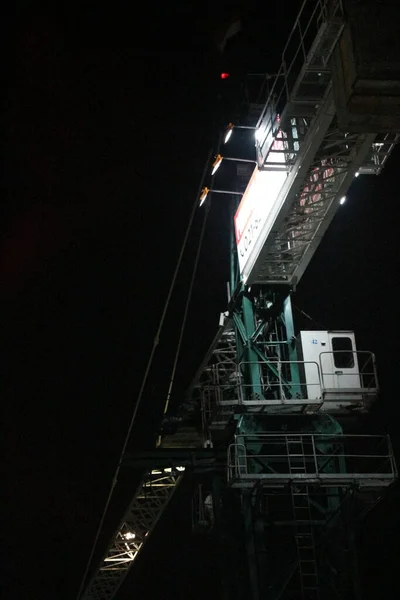 Tower crane working at night. the lighting is not too much, it only illuminates some parts of the tower crane. Tower cranes are usually used to build tall buildings.