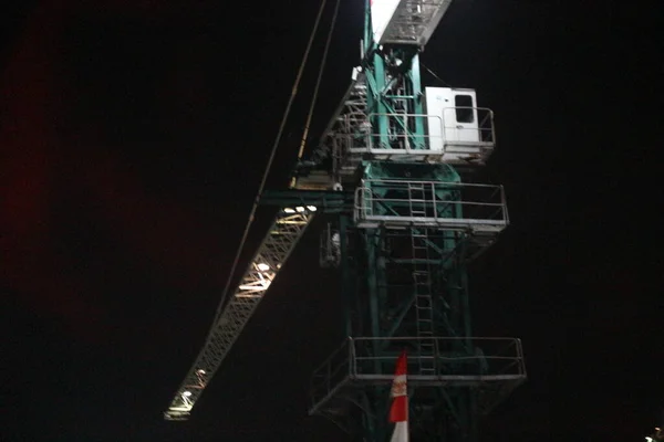 Tower crane working at night. the lighting is not too much, it only illuminates some parts of the tower crane. Tower cranes are usually used to build tall buildings.