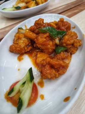 Sweet and sour chicken is fried chicken pieces with flour doused with a thick red-brown sweet and sour sauce. The original sweet and sour sauce recipe only consists of water, vinegar, tomato sauce, chili sauce, lemon juice, garlic, onions and starch 