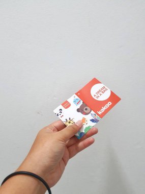 West Java, Indonesia in January 2023. Isolated white photo of a hand holding the KAKOO product brand tag. KAKOO is a plushie bag brand with various characters for boys and girls.