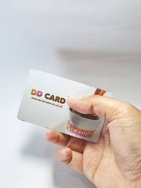 West Java, Indonesia on July 2022. Isolated photo of a hand holding a loyalty card, DD Card. With this card, every time you make a transaction at Dunkin Donuts, you will get points that can be exchanged for shopping vouchers.