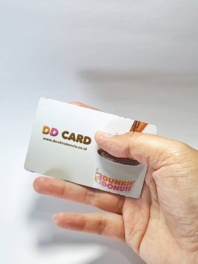 West Java, Indonesia on July 2022. Isolated photo of a hand holding a loyalty card, DD Card. With this card, every time you make a transaction at Dunkin Donuts, you will get points that can be exchanged for shopping vouchers.