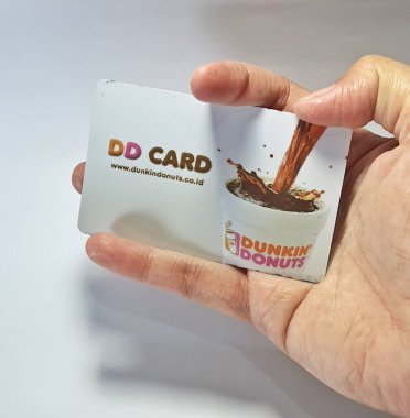 West Java, Indonesia on July 2022. Isolated photo of a hand holding a loyalty card, DD Card. With this card, every time you make a transaction at Dunkin Donuts, you will get points that can be exchanged for shopping vouchers.