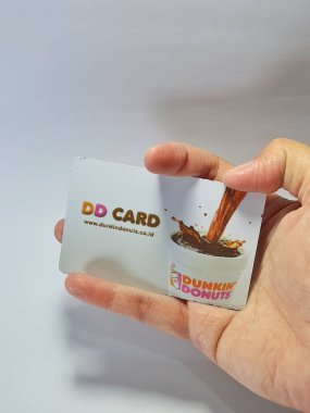 West Java, Indonesia on July 2022. Isolated photo of a hand holding a loyalty card, DD Card. With this card, every time you make a transaction at Dunkin Donuts, you will get points that can be exchanged for shopping vouchers.