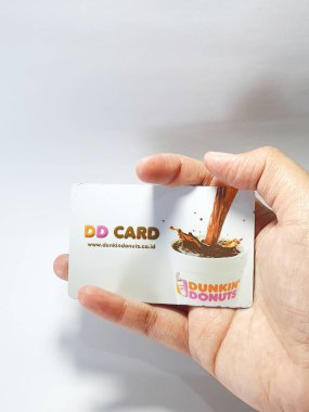 West Java, Indonesia on July 2022. Isolated photo of a hand holding a loyalty card, DD Card. With this card, every time you make a transaction at Dunkin Donuts, you will get points that can be exchanged for shopping vouchers.
