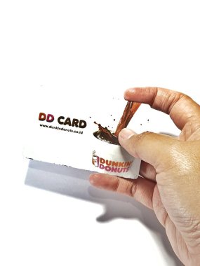 West Java, Indonesia on July 2022. Isolated photo of a hand holding a loyalty card, DD Card. With this card, every time you make a transaction at Dunkin Donuts, you will get points that can be exchanged for shopping vouchers.