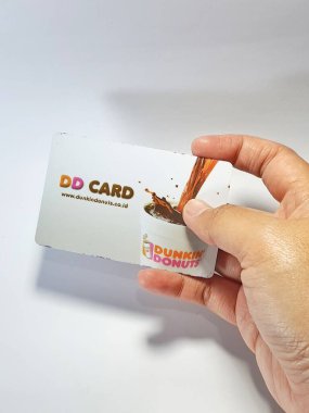 West Java, Indonesia on July 2022. Isolated photo of a hand holding a loyalty card, DD Card. With this card, every time you make a transaction at Dunkin Donuts, you will get points that can be exchanged for shopping vouchers.
