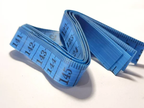 Isolated white photo of a sewing meter or fabric meter in blue. This multi-function measuring tool can be used not only to measure cloth, but also to measure body circumference and height.