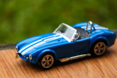 West Java, Indonesia in May 2022 Ford Cobra vintage toy racing car with bokeh background. Blue in color with white stripes, has 2 seats.