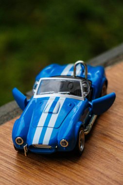 West Java, Indonesia in May 2022 Ford Cobra vintage toy racing car with bokeh background. Blue in color with white stripes, has 2 seats.