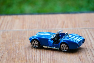 West Java, Indonesia in May 2022 Ford Cobra vintage toy racing car with bokeh background. Blue in color with white stripes, has 2 seats.