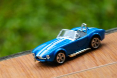 West Java, Indonesia in May 2022 Ford Cobra vintage toy racing car with bokeh background. Blue in color with white stripes, has 2 seats.