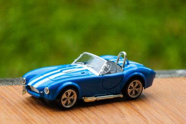 West Java, Indonesia in May 2022 Ford Cobra vintage toy racing car with bokeh background. Blue in color with white stripes, has 2 seats.