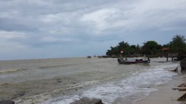 A fishing boat that is tossed about by the waves on a beach in the Semat area, Jepara, Central Java. The sea conditions look dirty, the weather in December is very bad on the Pantura.