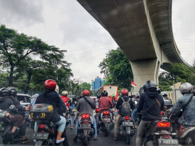 Jakarta, Indonesia in July 2022. There is a traffic jam under the Becakayu Toll Road, where motorbikes are stopping and moving slowly.