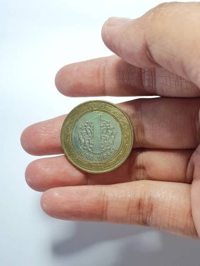 Turkey in June 2022. Isolated white photo of a hand holding a Turkish one lira coin. Lira is the currency of Turkey.