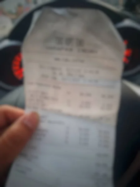 Defocused Blurred Photo Hand Holding Shopping Receipt Which Displays List — стоковое фото