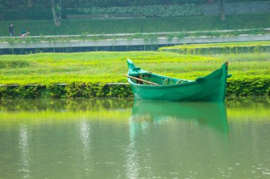 Yolcuları olmayan yeşil bir tekne gölün kenarına park edildi. Bu yeşil tekne gölün ortasındaki parkın bakımı için kullanılır. Endonezya haritası şeklinde bir bahçe Taman Mini Endonezya 'da.