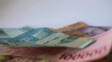 Bir elin rupiah kağıdını sayfa sayfa aldığı bir video. Bu paranın çekilmesi kişisel finans, aile mali yönetimi veya tatil tasarrufları ile ilgili resimler için uygundur.