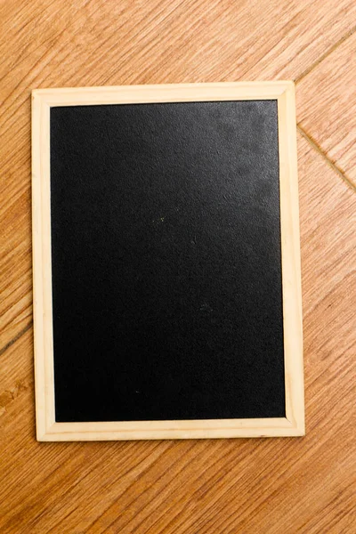 Malá Černá Tabule Dřevěným Rámem Spočívá Hnědé Dřevěné Texturované Podlaze — Stock fotografie