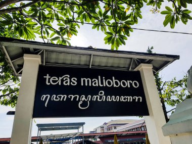 Yogyakarta, Endonezya Mart 2022. Malioboro Teras Malioboro tabelasında Latin alfabesi ve Cava harfleri var. Yazı, siyah tabanlı ya da arka planlı sarımsı beyaz renkte. Malioboro terası tüccar ve alıcıların toplandığı bir yer.