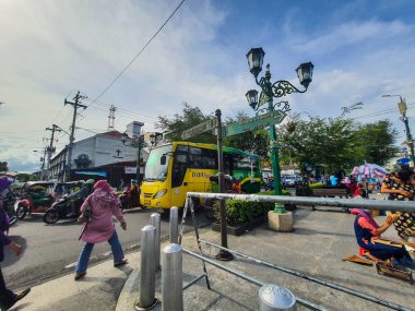 Yogyakarta, Endonezya Temmuz 2022. Trans Jogja otobüsü Malioboro caddesinden geçiyor. Otobüs trans jogja logosuyla yeşile boyandı, BPD DIY Bankası ve otobüsün arkasında KM 0 Jogjakarta anıtı var..