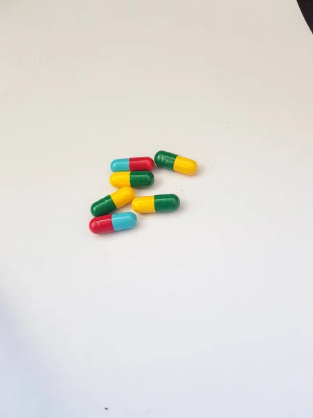 いくつかの青と赤の薬カプセルと緑と黄色のカプセルの分離された白い写真 医療用カプセルには用途によって様々な色があります — ストック写真