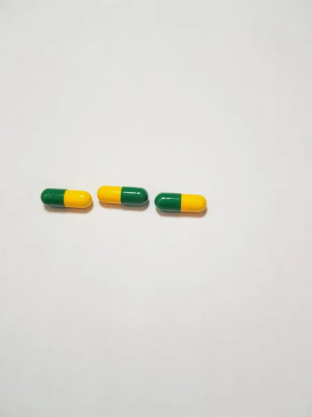 三片药物胶囊的分离白照片 胶囊是绿色和黄色的 — 图库照片