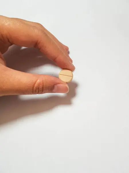 Kahverengi Ilaç Tableti Tutan Bir Elin Izole Edilmiş Beyaz Fotoğrafı — Stok fotoğraf