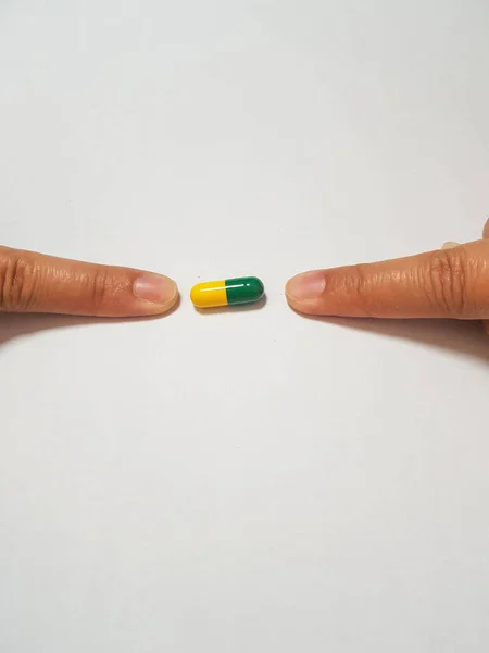 緑と黄色の薬カプセルを指している2本の額の孤立した白い写真 一つの図は 薬物研究 右の患者のための適切な薬に関連しています — ストック写真