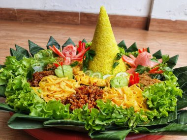 Nasi Tumpeng çok güzel dekore edilmiş sarı pirinç ve çeşitli mezeler içerir, yani orek tempeh, kızarmış tavuk, omlet, doğranmış et ve çeşitli sebzeler..