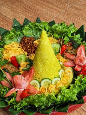 Nasi Tumpeng çok güzel dekore edilmiş sarı pirinç ve çeşitli mezeler içerir, yani orek tempeh, kızarmış tavuk, omlet, doğranmış et ve çeşitli sebzeler..