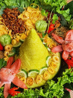 Nasi Tumpeng çok güzel dekore edilmiş sarı pirinç ve çeşitli mezeler içerir, yani orek tempeh, kızarmış tavuk, omlet, doğranmış et ve çeşitli sebzeler..