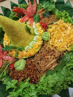 Nasi Tumpeng çok güzel dekore edilmiş sarı pirinç ve çeşitli mezeler içerir, yani orek tempeh, kızarmış tavuk, omlet, doğranmış et ve çeşitli sebzeler..