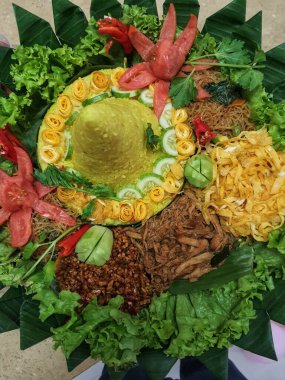 Nasi Tumpeng çok güzel dekore edilmiş sarı pirinç ve çeşitli mezeler içerir, yani orek tempeh, kızarmış tavuk, omlet, doğranmış et ve çeşitli sebzeler..