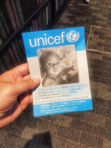 Kyoto, Japonya, 9 Ekim 2023. Bir el, üzerinde Japonca harfler olan UNICEF broşürü tutuyor. Gelişmekte olan ülkelerdeki çocuklara maddi yardım talebinde bulunmak amacıyla.