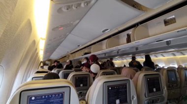 Medine, Suudi Arabistan, 3 Mart 2024. Umrah yolcuları memleketleri Endonezya 'ya dönmek üzere Suudi Arabistan Havayolları uçağına biniyorlar. Uçaktan Jakarta 'ya. Yolcular koltuklarını arasın..