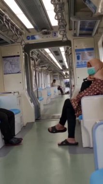 Jakarta, Endonezya, 2 Mayıs 2024. Jakarta LRT yolcuları cep telefonlarına bakmakla meşguller. Tren sessizdi, birçok koltuk boştu. İç kısımlara fildişi rengi beyaz ve mavi hakimdir..