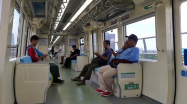 Jakarta, Endonezya, 2 Mayıs 2024. Jakarta LRT yolcuları cep telefonlarına bakmakla meşguller. Tren sessizdi, birçok koltuk boştu. İç kısımlara fildişi rengi beyaz ve mavi hakimdir..